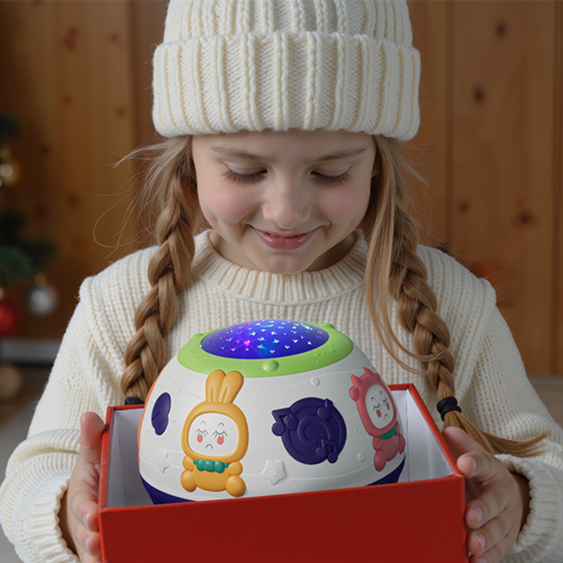 Child holding a dome-shaped baby night light projector and sound machine, featuring animal buttons around the sides and a star-patterned light top projecting colorful stars