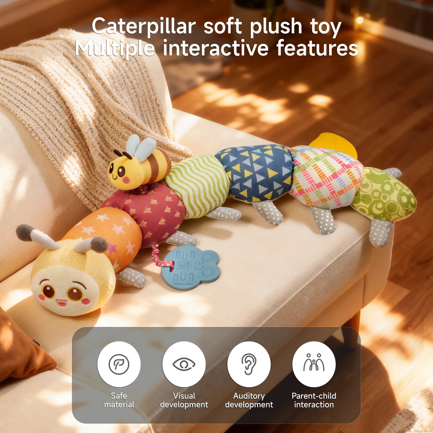 Stuffed animal caterpillar plush toy placed on a sofa, featuring multiple sensory elements like rattle, teether, and crinkle paper; promotes visual and auditory development, made from safe materials for parent-child interaction.